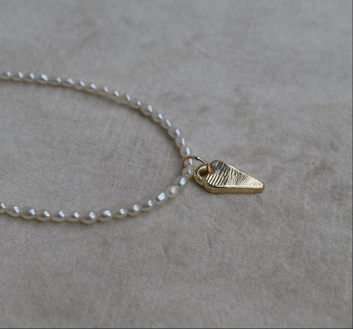 Rice shaped fresh water pearl hand strung necklace with 9ct gold tiffany heart charm. Pearl necklace measure 16” as standard with a 2” extension chain.All pieces are handmade to order. pearl charm necklace gold tiffany heart charm heart necklace tiffany pearl beaded strung necklace freshwater pearls pearl beach jewellery
