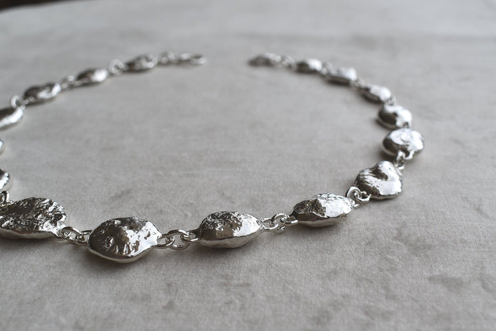 Silver pebble charms all linked together with a large handmade toggle clasp. This is a real heavy statement piece that is made to order and totally unique.
Unique silver pebble links make up this heavy statement necklace. Made to order from recycled silver each pebble is totally unique. Hallmarked for silver. silver nugget chain necklace silver charms linked together. heavy silver pebble pendant
Chunky silver nugget heavy silver chain necklace. Heavy link hermes chain choker.