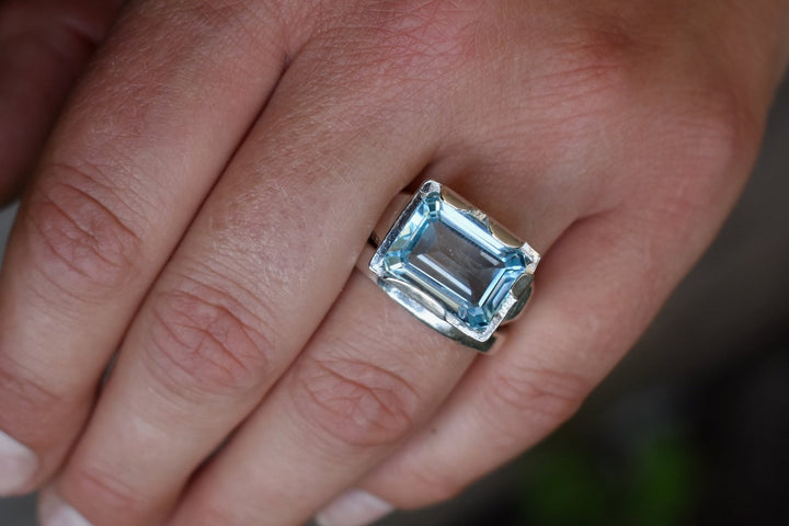 This is a beautiful emerald cut blue topaz set into a hand made solid silver setting. This stone is ethically sourced and the silver is 100% recycled 
blue topaz statement ring cocktail party style large engagement ring in silver emerald cut stone ring diamond ring tiffany engagement sparkle silver stack ring