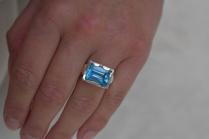 This is a beautiful emerald cut blue topaz set into a hand made solid silver setting. This stone is ethically sourced and the silver is 100% recycled 
blue topaz statement ring cocktail party style large engagement ring in silver emerald cut stone ring diamond ring tiffany engagement sparkle silver stack ring
