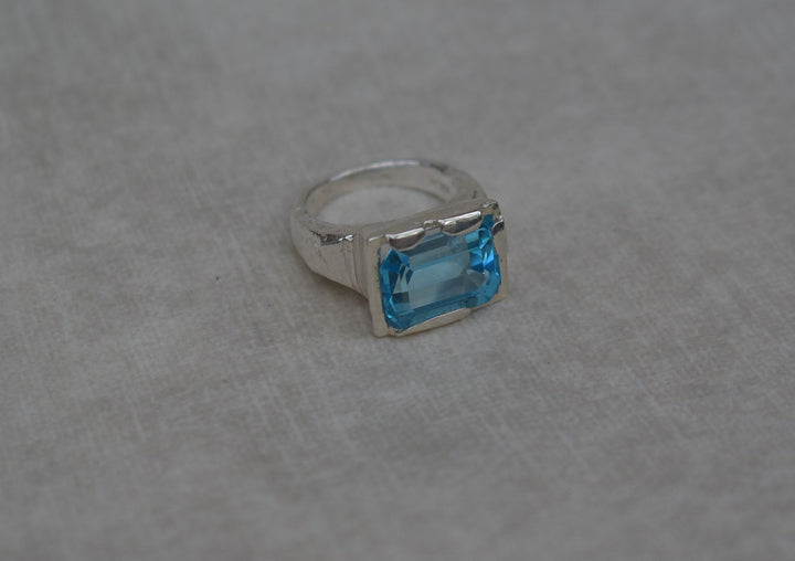 This is a beautiful emerald cut blue topaz set into a hand made solid silver setting. This stone is ethically sourced and the silver is 100% recycled 
blue topaz statement ring cocktail party style large engagement ring in silver emerald cut stone ring diamond ring tiffany engagement sparkle silver stack ring