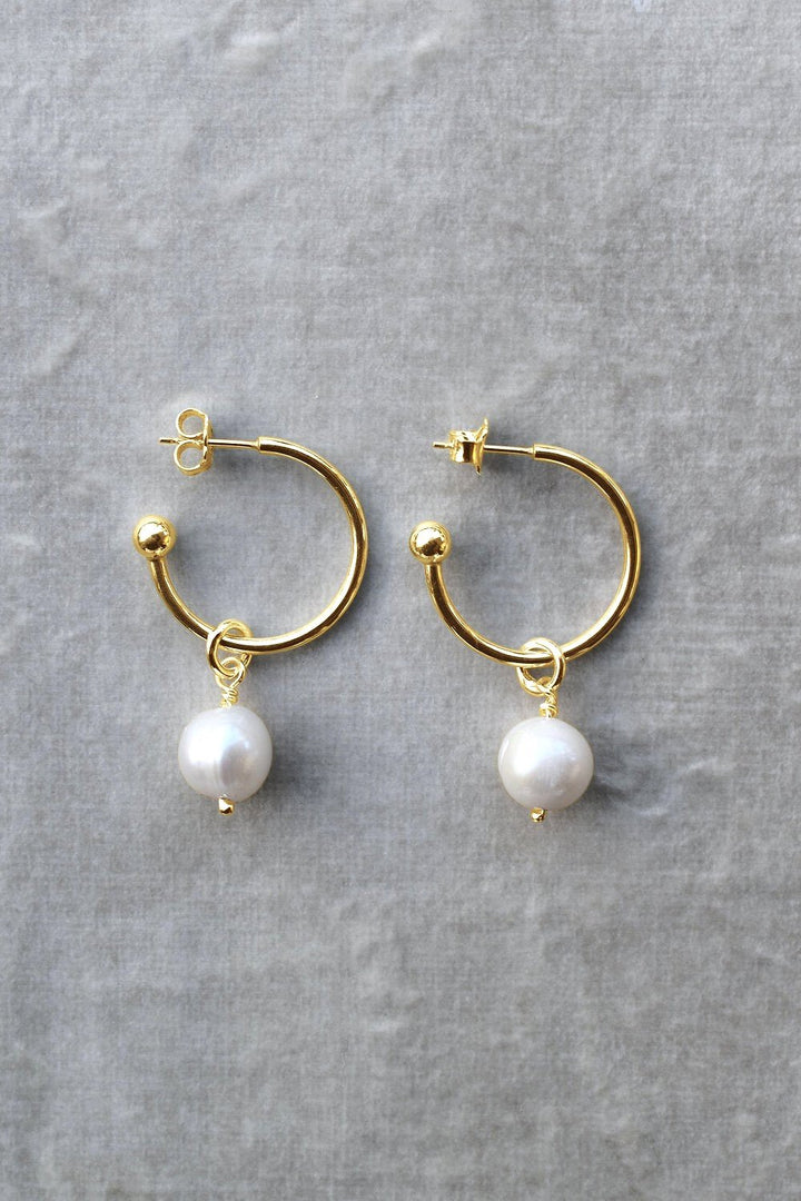 Large hoop earrings in 9ct yellow gold with white freshwater pearl drops, displayed on a textured grey background. gold hoop earrings pearl earrings hoops with charm