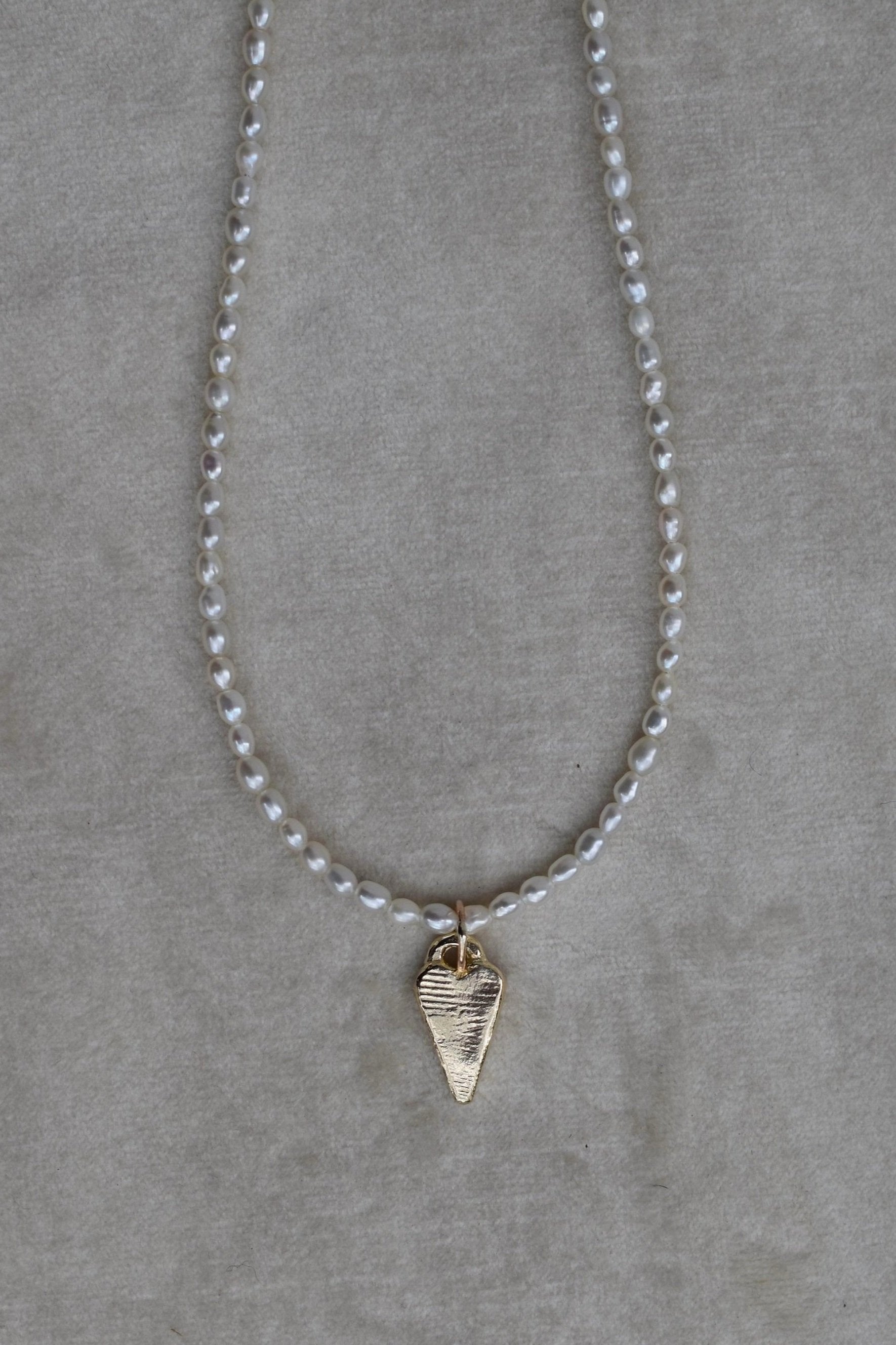 Rice shaped fresh water pearl hand strung necklace with 9ct gold tiffany heart charm. Pearl necklace measure 16” as standard with a 2” extension chain.All pieces are handmade to order. pearl charm necklace gold tiffany heart charm heart necklace tiffany pearl beaded strung necklace freshwater pearls pearl beach jewellery
