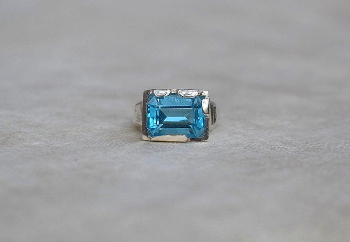 This is a beautiful emerald cut blue topaz set into a hand made solid silver setting. This stone is ethically sourced and the silver is 100% recycled 
blue topaz statement ring cocktail party style large engagement ring in silver emerald cut stone ring diamond ring tiffany engagement sparkle silver stack ring
