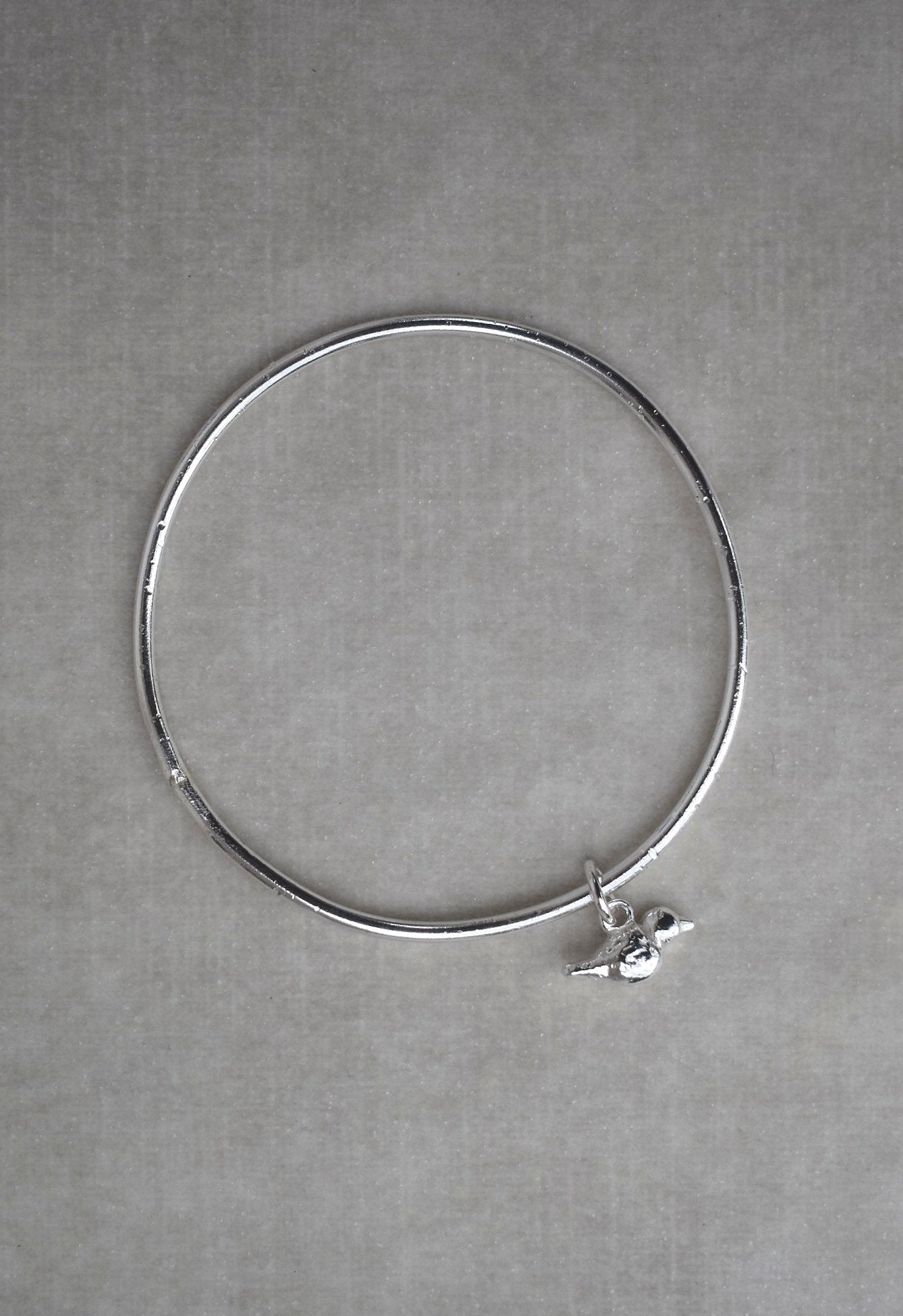 Solid silver round wire bangle with a mini bird charm. handmade to order. Solid silver round wire bangle with a mini bird charm. Can be worn alone or with a combination of other bangles from the collection. Round thick silver stack bangle silver cuff charm bracelet round solid silver bangle ladies bracelet with charm personalised word bracelet bangle stack silver. bird jewellery silver bird charm.