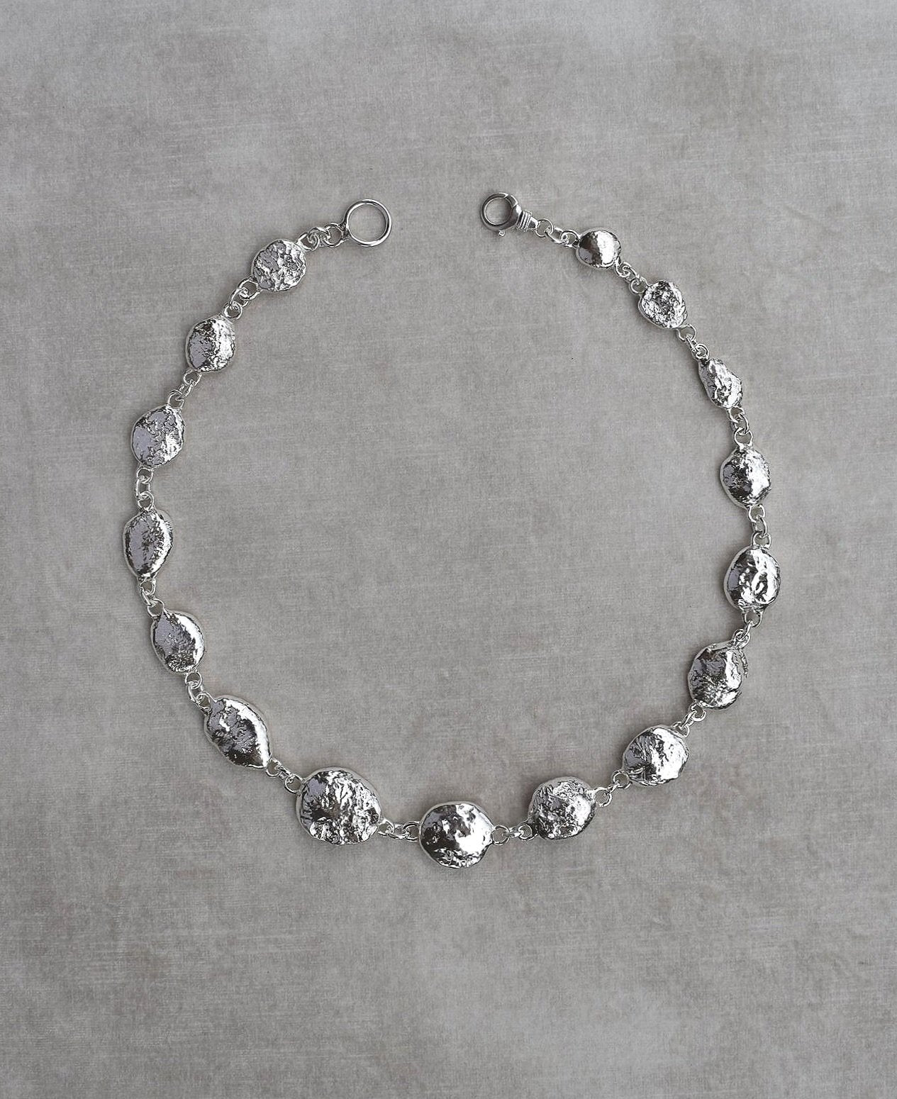 Silver pebble charms all linked together with a large handmade toggle clasp. This is a real heavy statement piece that is made to order and totally unique.
Unique silver pebble links make up this heavy statement necklace. Made to order from recycled silver each pebble is totally unique. Hallmarked for silver. silver nugget chain necklace silver charms linked together. heavy silver pebble pendant
Chunky silver nugget heavy silver chain necklace. Heavy link hermes chain choker.